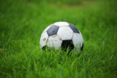 Çimlerin üzerinde eski bir futbol topu. Futbol ekipmanları.