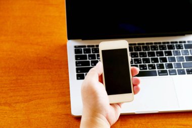 Akıllı telefonla uzaktan çalışan bir adamın elinde dizüstü bilgisayar var..