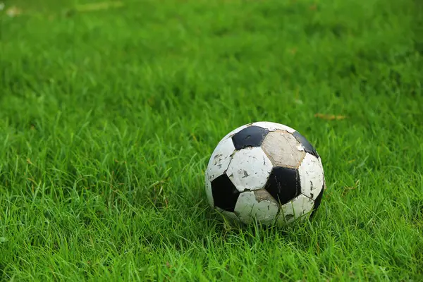 Old soccer ball on the grass. Football equipment.
