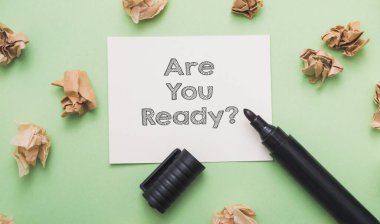 Card with question Are You Ready black marker and crumpled papers on green background upper view. Step-by-step guide for start-up business