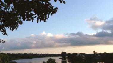 timelapse of floating clouds in sunset sky in summer against background of river