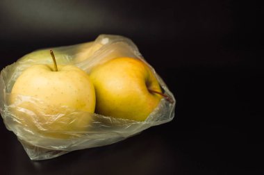 İçinde iki elma olan plastik bir torba. Taze elmalar, geri dönüşümsüz plastikle kaplanmış.