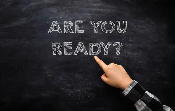 A hand pointing at a chalkboard with the words Are you ready written below it, illustrating a business concept.