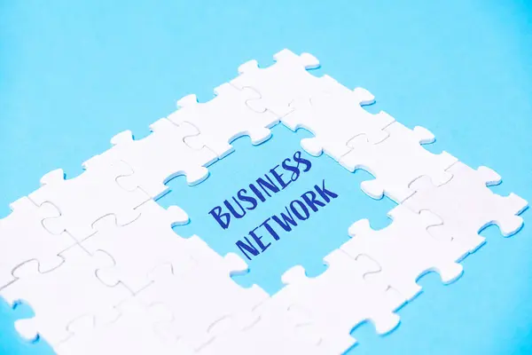 A white puzzle piece with the word business network written in blue. The puzzle piece is missing a piece, creating a sense of incompleteness and intrigue