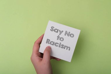 Irkçılığa hayır diyen bir kağıt parçasını tutan bir el. Görüntü ırkçılığa karşı güçlü bir mesaj veriyor ve insanları buna karşı durmaya teşvik ediyor.
