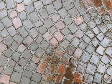 Islak yüzeyi olan bir tuğla geçit. Tuğlalar kahverengi ve gri.