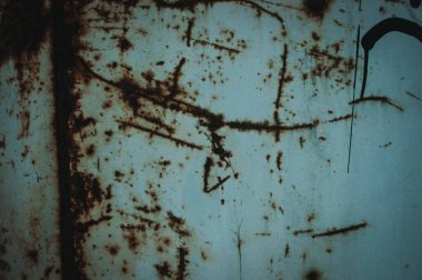 Üzerinde bir sürü çizik ve çizik olan mavi bir duvar. Duvar eski ve yıpranmış.