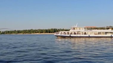 Arka planda köprü olan bir tekne gölde seyahat ediyor. Gökyüzü açık ve su sakin.