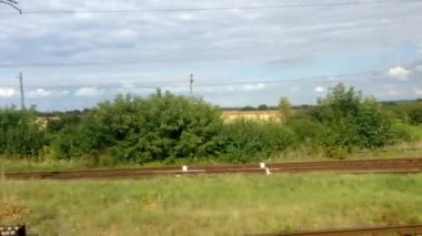 Arka planda çimenlik bir alan olan bir tren raylarda ilerliyor. Görünürdeki tek şey tren.