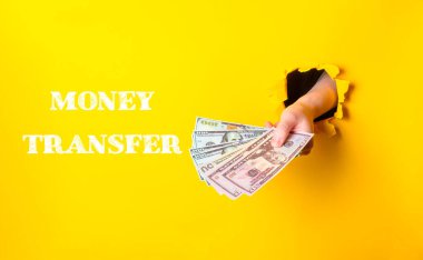 Bir kişi bir tomar para tutuyor ve para transferi kelimeleri onun üzerinde yazılı.