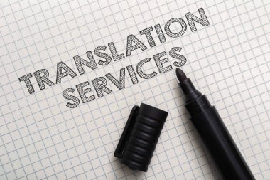 Çeviri hizmetleri farklı diller arasında iletişim kurmanın bir yoludur. El yazısı ile yazılmış bir kağıt parçasının üzerinde bir işaret. İşaret siyah ve siyah başlığı var.