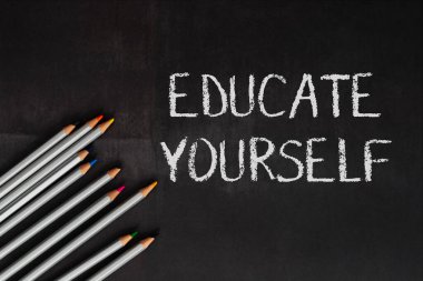 Üzerinde kendini eğittiğin kelimelerin yazılı olduğu bir yazı tahtası. Karatahta farklı renklerde bir sıra kalemle çevrili.