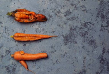 Üç havuç gösteriliyor, biri ikiye bölünmüş. Diğer ikisi bir bütün. Çirkin sebzeler, yiyecek organik atık azaltma