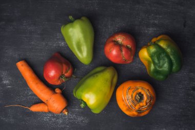 Tezgahta havuç, domates ve dolma biber gibi çeşitli sebzeler sergilenmektedir. Çirkin sebzeler, yiyecek organik atık azaltma