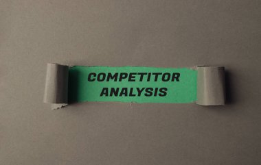 Üzerinde rakip analizi yazan yırtık bir kağıt parçası. Kağıt yeşil ve buruşuk görünüyor.