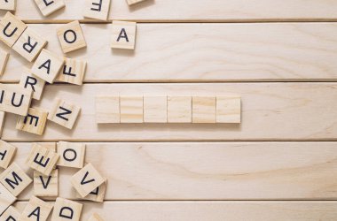 Tahta tahtada bir sürü harf ve ortasında bir kelime yazılı. Harfler tahtanın her yerine dağılmış ve kelime beş tahta bloktan oluşuyor.