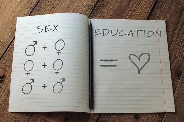 Üzerinde kurşun kalem ve kalp olan bir defter. Defter, üzerinde Seks Eğitimi yazan bir sayfayı açıyor.