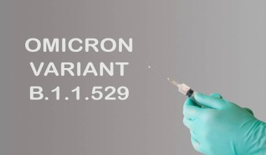 Beyaz arka planda Omicron Varyantı yazan bir şırınga tutan kişi