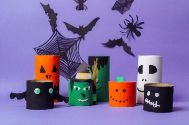 Bir grup Cadılar Bayramı temalı kağıt fener mor bir arka planda sergilenir. Fenerler yüzler ve diğer Cadılar Bayramı sembolleriyle süslenmiş.