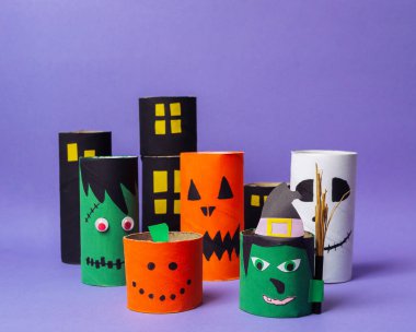 Cadılar Bayramı temalı üzerinde yüzler çizilmiş kağıt tüplerden oluşan bir grup. Tüpler arka arkaya dizilmiş, bazıları diğerlerinden daha uzun. Sahne şenlikli ve eğlenceli.