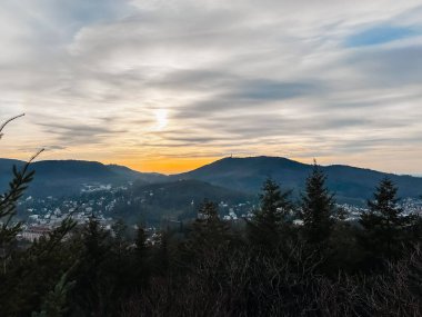 Arka planda günbatımı olan güzel bir dağ sırası. Gökyüzü bulutlu ve güneş batıyor.