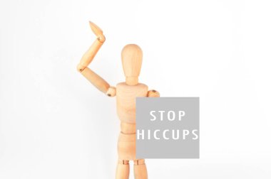 Wooden figure is holding a sign that says Stop Hiccups. Concept of humor and playfulness, as the figure is posed in a silly manner and the sign is a lighthearted way to address a common problem clipart