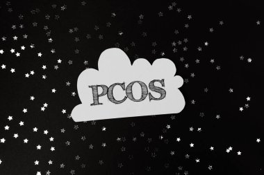Yıldızlı bir gökyüzünün siyah ve beyaz görüntüsü. Beyaz harflerle yazılmış Pcos kelimesi. Karanlık gökyüzünde parlayan yıldızlar gibi gizem ve merak kavramı