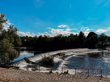 Güzel mavi bir gökyüzü, birkaç bulut ve bir nehir. Su sakin ve ağaçlar yemyeşil
