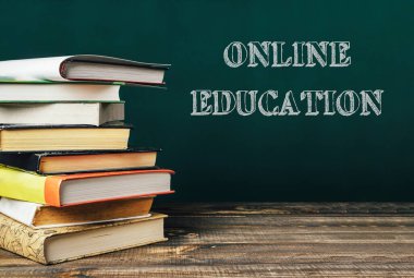 Üstünde online eğitim yazan bir yığın kitap var. Kitaplar üst üste yığılmış, bu da bir önem duygusu yaratıyor ve konuya vurgu yapıyor. Öğrenim ve eğitim kavramı