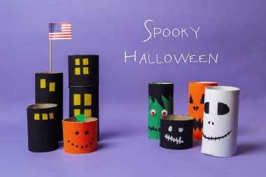 Poster of a city with a flag and the words spooky Halloween written below. The poster features a variety of Halloween themed paper tubes, including a pumpkin, a skeleton, and a monster clipart