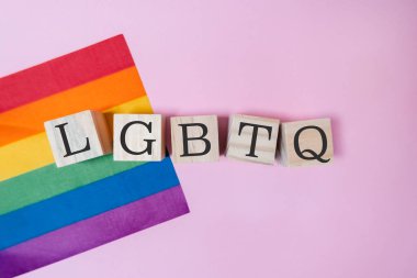 Gökkuşağı bayrağı LGBTQ ile pembe bir arkaplanda sergilenmektedir. Harfler bir blok biçiminde düzenlenir, görsel olarak çekici ve yaratıcı bir görüntü yaratır.