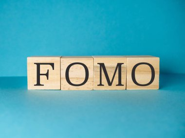 Üzerinde FOMO harfleri yazan tahta blok. Blok bir kelime gibi görünecek şekilde düzenlenmiş. Basitlik ve minimalizm kavramı