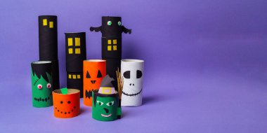 Üzerinde cadılar bayramı yüzleri olan bir sürü kağıt tüp. Tüpler sırayla dizilmiş ve farklı boyutlarda.