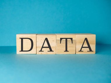 Üzerinde DATA harfleri olan tahta blok mavi bir arka planda. Blok, veriyi yaratıcı ve sanatsal bir şekilde heceleyecek şekilde düzenlenmiştir.