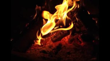 Ateş odun yığınında yanıyor. Ateş turuncu ve sarı.