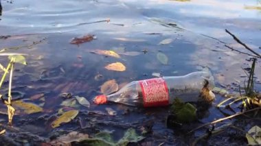 Bir şişe Coca-Cola bir su kütlesinin içinde yüzüyor. Şişe kısmen suya batırılmış ve su bulanık ve kirli. Kirlilik ve çevresel bozulma kavramı