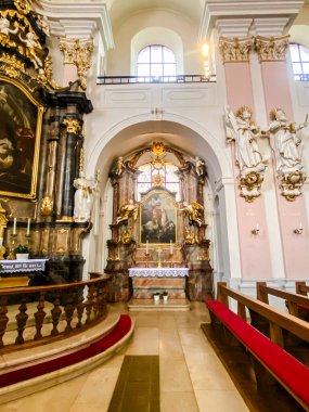 Kilisenin içinde büyük bir sunak ve bir kadın ve çocuk tablosu var. Sunak, kilise sıraları ve kırmızı halılarla çevrili.