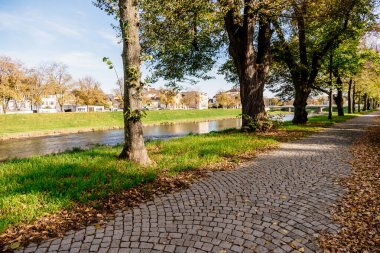 İçinden nehir akan bir park ve bir patika. Yol tuğladan yapılmış ve ağaçlarla kaplı.