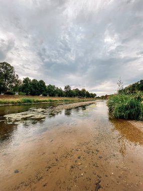 Arka planda bulutlu bir gökyüzü olan nehir. Su bulanık ve gökyüzü kapalı.