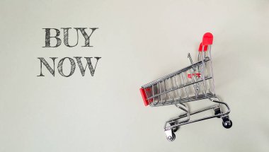 Satın alma sözlerinin yazılı olduğu alışveriş arabası. Araba küçük ve metalden yapılmış.