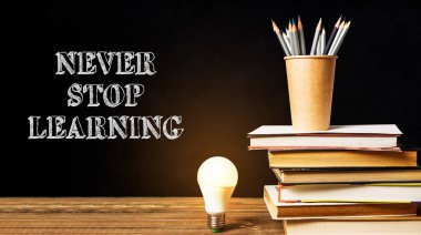 Üstünde bir ampul olan kitap yığını ve altında 