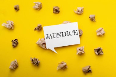 Üzerinde sarılık yazan beyaz bir tabela. Tabela sarı arkaplanın üstünde.