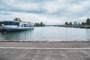 Basel, İsviçre - 13 Mayıs 2023 - Tekne rıhtıma yanaştı. Su sakin ve gökyüzü bulutlu. Tekne beyaz ve mavi.