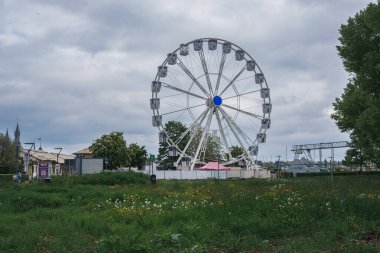 Basel, İsviçre - 13 Mayıs 2023 - Büyük beyaz dönme dolap çimen tarlasında. Gökyüzü bulutlu ve çimenler yeşil