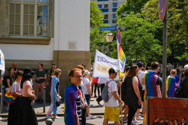 Karlsruhe, Almanya - 3 Haziran 2023 - Bir grup insan ellerinde gökkuşağı bayraklarıyla sokakta yürüyorlar. Sahne kutlama ve neşe dolu, çünkü insanlar bir onur yürüyüşüne katılıyor.