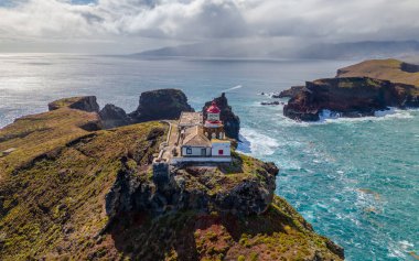 Madeira 'daki Sao Lourenco yarımadasındaki havadan deniz feneri. Farol da Ponta de So Loureno, Madeira. Okyanus kıyısındaki küçük bir adada deniz feneri, dalgalar, bulutlar....