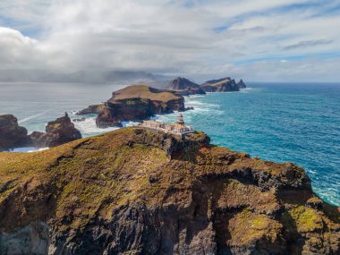 Madeira 'daki Sao Lourenco yarımadasındaki havadan deniz feneri. Farol da Ponta de So Loureno, Madeira. Okyanus kıyısındaki küçük bir adada deniz feneri, dalgalar, bulutlar....