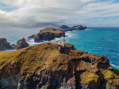 Madeira 'daki Sao Lourenco yarımadasındaki havadan deniz feneri. Farol da Ponta de So Loureno, Madeira. Okyanus kıyısındaki küçük bir adada deniz feneri, dalgalar, bulutlar....