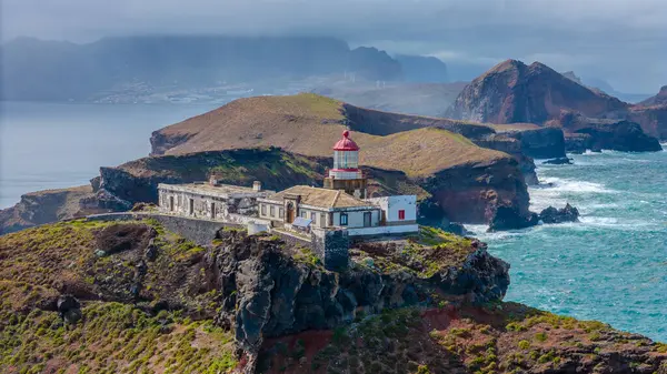 Madeira 'daki Sao Lourenco yarımadasındaki havadan deniz feneri. Farol da Ponta de So Loureno, Madeira. Okyanus kıyısındaki küçük bir adada deniz feneri, dalgalar, bulutlar....