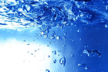 Akvaryumdaki su yüzeyinin altında köpüren su, yakın plan birçok mavi hava kabarcığı.